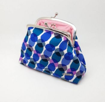 This purse is made from a fabric with beautiful bright shades of blue with pink and black mixed in on a white background. The lining is a soft pink fabric for added luxury every time you open the purse. This is a purse made to hold all your essentials. It easily carries coins and notes in the internal coin purse and has two bank card pockets on each side of the external purse. There is also room for a phone and a lipstick. It can also be used as a cosmetic bag. 