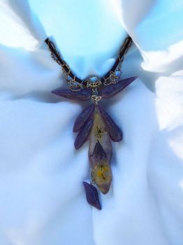 A striking handmade necklace with real Irish wildflowers in resin, purple accents, and a faux suede + chain combination. Pendant size: 8×7 cm.