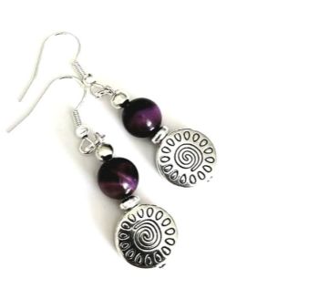 Introducing Rowena…. Beautiful earrings created with antique silver spiral drops, gorgeous natural Tiger’s eye gemstones in deep purple (dyed), silver plated, nickel free ear wires. The drop on these earrings is approx. 3.17cm/1.25ins.. Lightweight and easy to wear… Enhance your look with these beautiful bespoke pieces…. They arrive in a pretty organza bag….. and have free Shipping!
Tiger's Eye is often used as a protective amulet, said to deflect negative energies and promote safety and security. It is thought to help dispel negative thoughts and emotions, encouraging a more positive mindset.