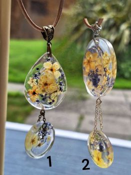 Double resin pendants with real flowers and chain detail on soft faux suede. 2 styles available. Price per necklace.