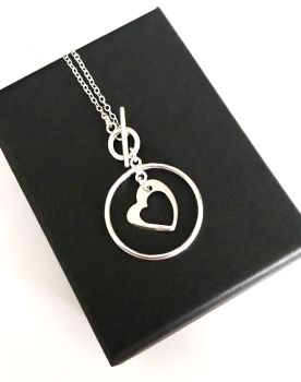 Handmade pendant, created with a silver plated frame, clasp and chain, and a highly polished stainless steel heart charm . This pendant is light and easy to wear.. so versatile and suitable for any season… The chain is approx. 50.8cm/20ins in length, and the pendant is approx. 3.17cm/1.25ins in length/width….. Elevate your style with this gorgeous bespoke piece! It arrives in a pretty organza bag, and has free shipping!