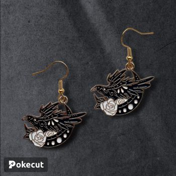 A lovely black, white and gold enamel charm of a crow. There is a small white flower as well as a moon in the background. 