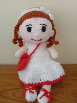 Crochet doll with auburn hair and red shoulder bag.