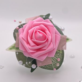 A pretty keepsake debs flower corsage made with an artifical baby pink rose and attached to a white pearl bracelet.&nbsp;