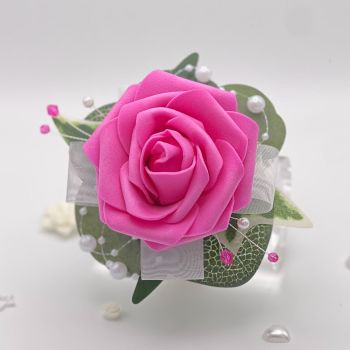 A pretty keepsake debs flower corsage made with an artificial deep pink rose and attached to a white pearl bracelet.