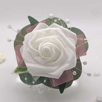 A pretty keepsake debs flower corsage made with an artificial white pink rose and attached to a white pearl bracelet.
