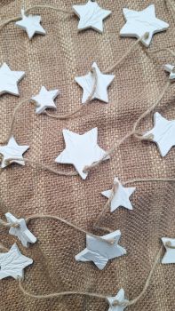 Handmade with air dry clay, this gorgeous rustic garland comprises of 21 stars varying sizes from 2cm - 5cm. It's approx 1.7 metres in length. Each star is tied in place to a length of jute string. Some.stars are plain and others are imprinted with evergreen foliage.
These clay decorations will last for years and years once used indoors only and stored away from damp conditions