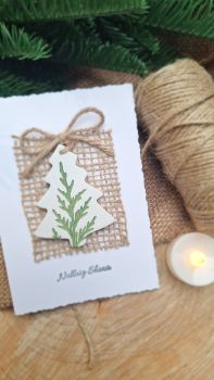 A beautiful crisp white greetings card, blank on inside. The card is adorned with a detachable clay ornament on a length of string to hang on your Christmas tree. 