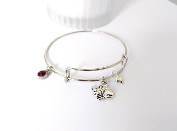 Gorgeous polished stainless steel adjustable bangle, with a cute antique silver cat charm, silver plated heart charm and a silver tone charm with a faceted glass bead in deep red.&nbsp; Light and easy to wear, and perfect for cat lovers!&nbsp; It arrives in a pretty organza bag, and has free shipping