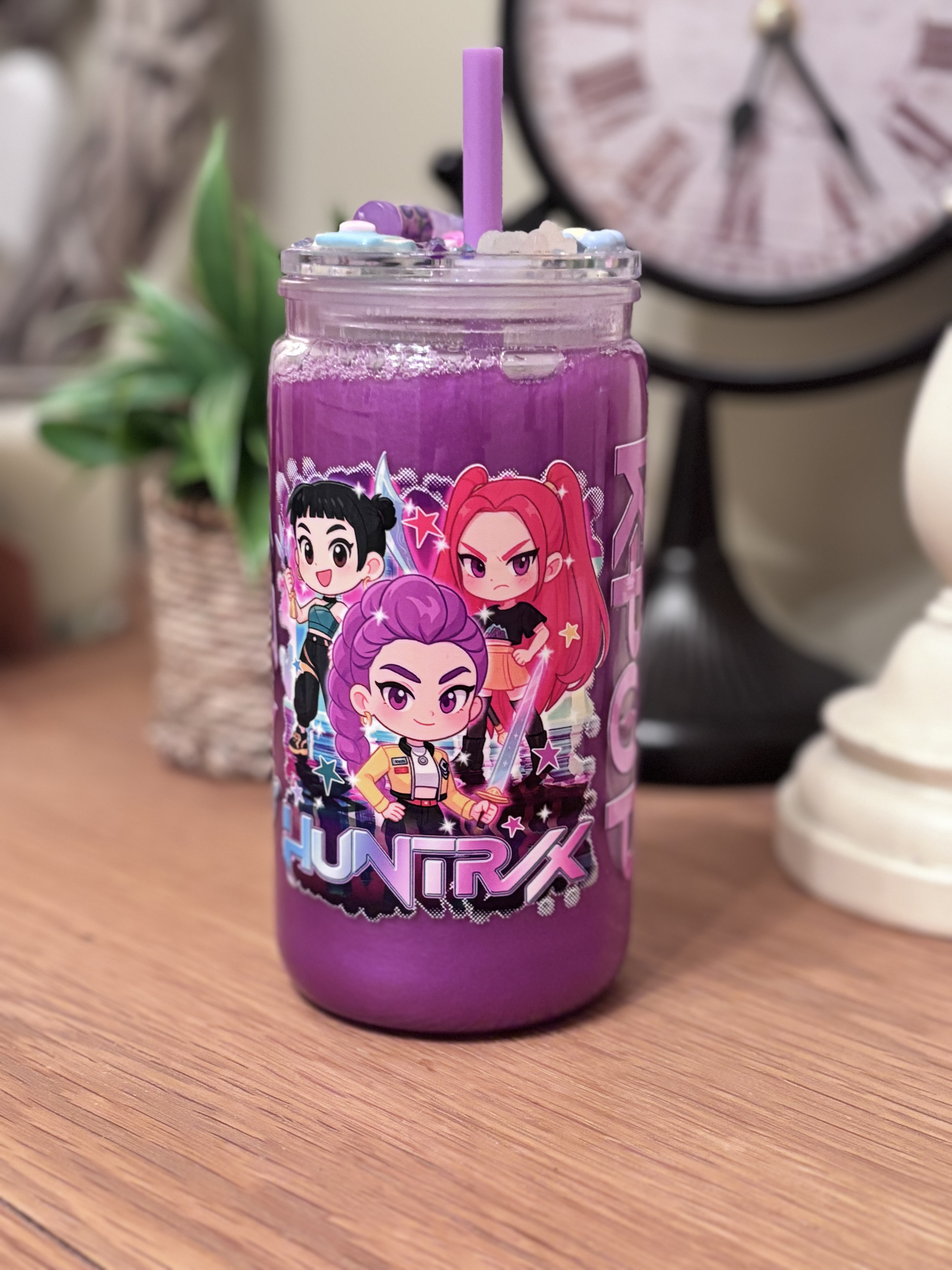 A bold and vibrant 16oz acrylic tumbler filled with shimmering mica powder liquid, featuring a fun K-Pop&ndash;inspired Demon Hunters design and a matching decorative topper. A perfect gift for teens, K-Pop fans, and lovers of colourful, eye-catching drinkware.