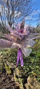 Wrapped in textured semi-sheer white paper and finished with a generous flowing lavender-purple satin ribbon bow, this arrangement exudes boho-chic sophistication with a vintage, moonlit romance.
