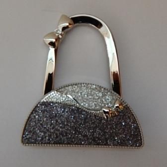 Handbag hooks are a functional accessory and very easy to use.
Perfect to keep your bag off the floor and allows you keep your bag in your view at all times.
It can also be hung on your bag as a decoration.
Two tone silver&nbsp; handbag shaped bag hook.