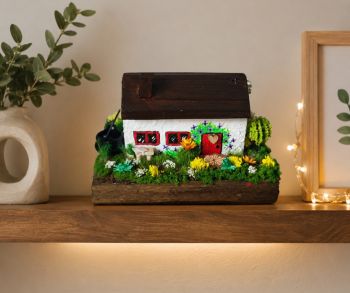 This tiny Irish cottage brings the charm os the countryside to your home. Expertly crafted with realistic moss and dried flowers to mirror the lush landscape of Ireland. It's a small piece of heritage built by hand&mdash;10/8/6 cm.