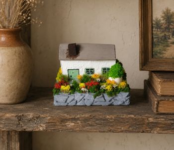 Capture the charm of the Irish countryside with this unique, handcrafted miniature. Built from reclaimed wood and painted with acrylic colours, this piece features a classic cottage with a vibrant garden and rustic elements. 9/7/6 cm.