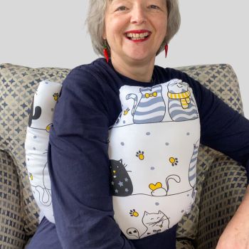 This gift set combines breast cancer surgery recovery pillow and matching chemo port seatbelt pillow are ideal for use directly after surgery, or in the following weeks while healing takes place. This BC support pillow is shaped to fit comfortably under the affected arm, and is filled with high quality polyester filling to a fairly firm finish, perfect to provide adequate support and comfort. This pillow reaches mid chest in width, so it will easily cover the surgery area, and provide support&nbsp; and padding. The chemo port support pillow gives support when used in a car while treatment is ongoing and afterwards.
The BC pillow measures 43cm wide X 37cm long and 10 cm in depth. The chemo port support pillow measures 18cm wide X 8cm long and 4cm in depth. This large grey, white, black cats print is soft and breathable. All pillows come with a handmade with love by Rodgerson Handcraft label and are reversible.
