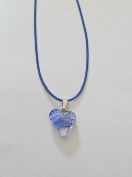 A small crystal heart on a leather rope necklace. The leather is coloured blue to match the gem. The heart has blue swirls of colour inside the clear crystal