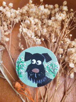Unique hand-painted wooden magnet features a cute black dog with a soft background and tiny white flowers!