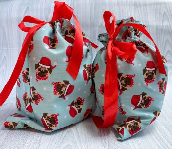 This gift bag set are made using Pugs wearing Santa hats fabric. This gift bag set includes 2 gift bags. They are finished to a high standard, are fully lined in festive red cotton fabric and are drawstring tied with coordinating red ribbon. It is reusable gift wrapping and will make a great tradition for wrapping Christmas presents.&nbsp;