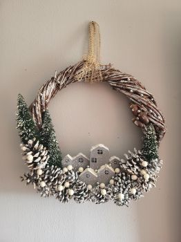 Handcrafted from scratch, this natural wreath is hand-woven from vine and natural pinecones. In the middle, you find handcrafted wooden houses painted with acrylic. 35/34 cm