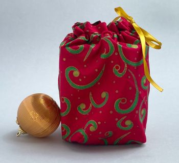 This gift bag is made using green and gold swirls on red fabric. This gift bag is finished to a high standard, and is drawstring tied with coordinating gold ribbon. It is reusable gift wrapping and will make a great tradition for wrapping Christmas presents.&nbsp;