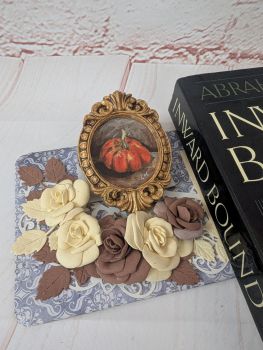 A miniature pumpkin painting in acrylic, set in a handmade gold-toned frame. The overall size, measured across the outer edge of the frame, is approximately 9 &times; 6.5 cm. Both the painting and frame are handmade, making this a unique little autumn piece.