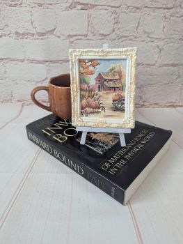 A hand-painted watercolour miniature of a smal autumn house, set in a handmade white frame