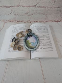 A hand-painted watercolour miniature featuring a lighthouse, set in a handmade oval frame.