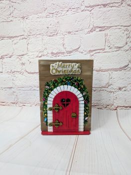 A handmade 13 &times; 18 cm Christmas keepsake with an opening wooden door revealing a festive scene inside