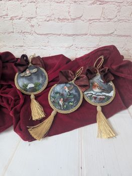 A set of three hand-painted Christmas ornaments featuring robins, holly and festive details.