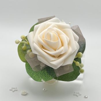 A pretty keepsake wrist corsage made with an artificial cream rose and attached to a cream pearl bracelet.