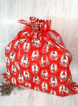 This gift bag is made using 100% cotton Christmas fabric featuring grey and red gnomes on red background fabric. This gift bag set is finished to a high standard and is drawstring tied with thick red sparkly ribbon. It is reusable gift wrapping.