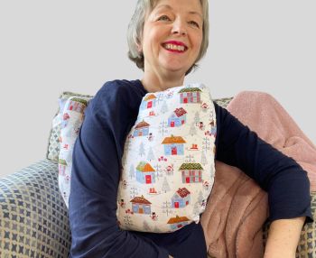 My breast cancer surgery support pillows are ideal for use directly after surgery, or in the following weeks while healing takes place. This support pillow is shaped to fit comfortably under the affected arm, and is filled with high quality polyester filling to a fairly firm finish, perfect to provide adequate support and comfort.
This pillow reaches mid chest in width, so it will easily cover the surgery area, and provide support&nbsp; and padding. It measures 43cm wide X 37cm long and 10 cm in depth. This blue houses and snowmen fabric is soft and breathable. All pillows come with a made with love by Rodgerson Handcraft label and are reversible.