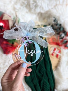 Add a touch of magic to your holiday decor with our beautiful handmade personalized Christmas baubles! Crafted from 2mm clear acrylic, each bauble features a name and initial personalized in vibrant vinyl, making it a perfect keepsake for your baby's first Christmas. Measuring approximately 75mm in diameter, these lovely ornaments come with a sheer organza ribbon, making them ideal gifts for loved ones. Choose your ribbon and initial color, and cherish this special memory for years to come!