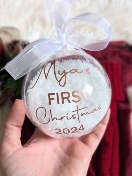 Celebrate a baby's first Christmas with our personalized snow-filled bauble, crafted from high-quality, eco-friendly plastic. These 80mm ornaments feature a delicate organza ribbon and a vinyl font available in various colours. Each bauble comes with "First Christmas 2024" as standard, making it a timeless keepsake. Perfect for your tree or as a thoughtful gift, these baubles are lovingly designed and handmade by our team.